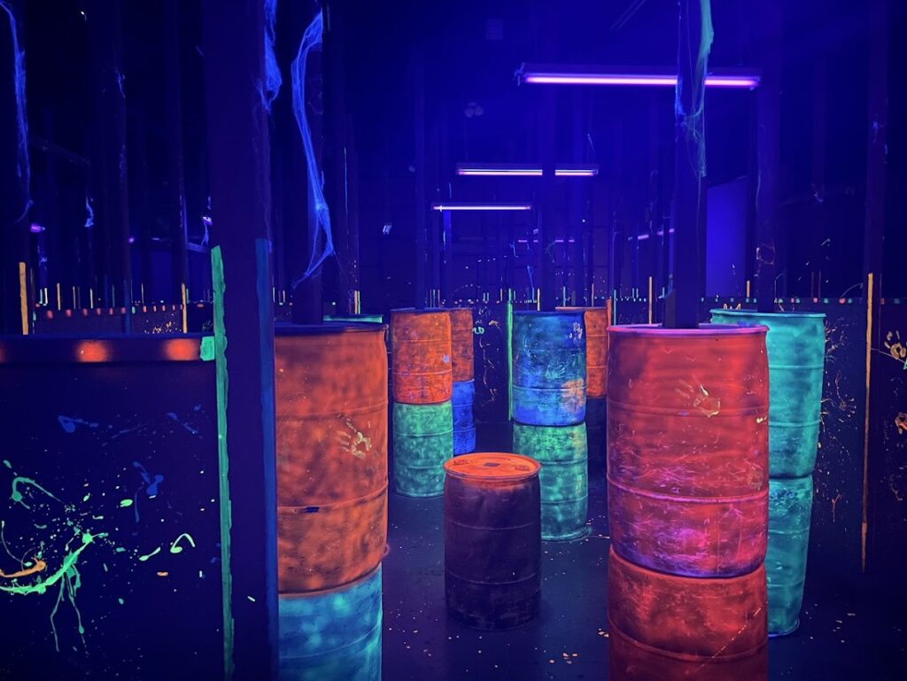 Glowing orange barrels used as cover in the laser tag arena