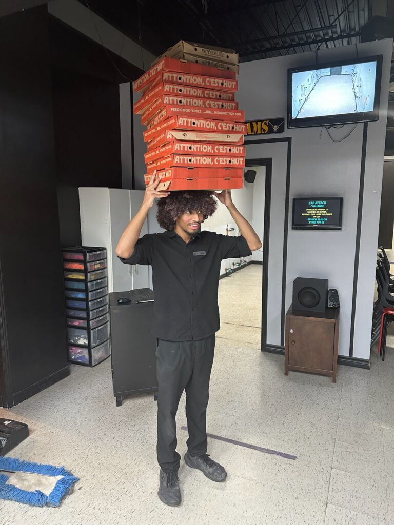 Zap Attack staff member balancing a stack of pizza boxes on his head