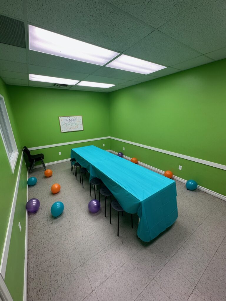 Green party room set up with a long table, balloons and a Happy Birthday sign