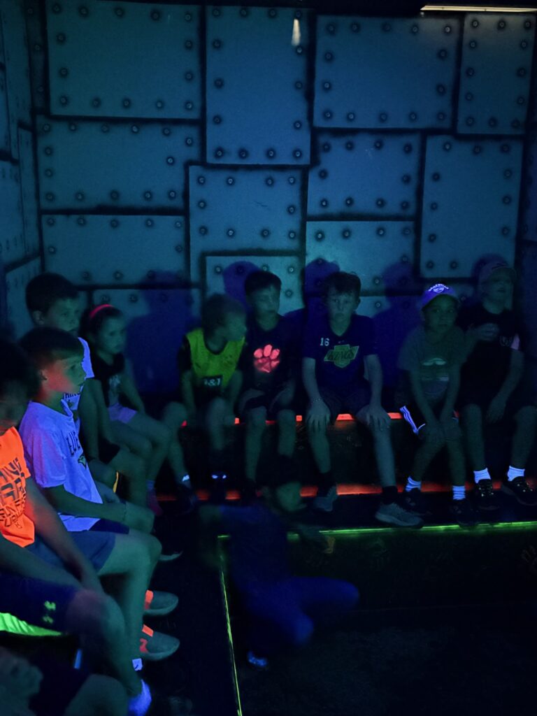 Kids in the black-lit briefing room before a laser tag game